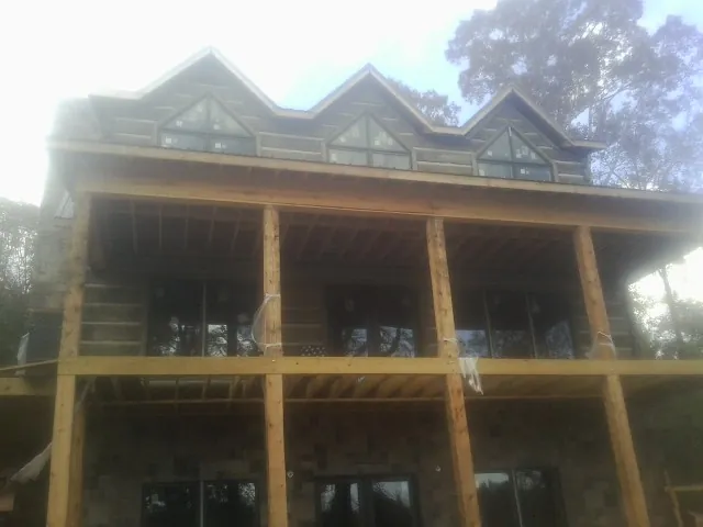 Dormers and porch framing on a large log home under construction — Roof Coating work by our crew in White Castle