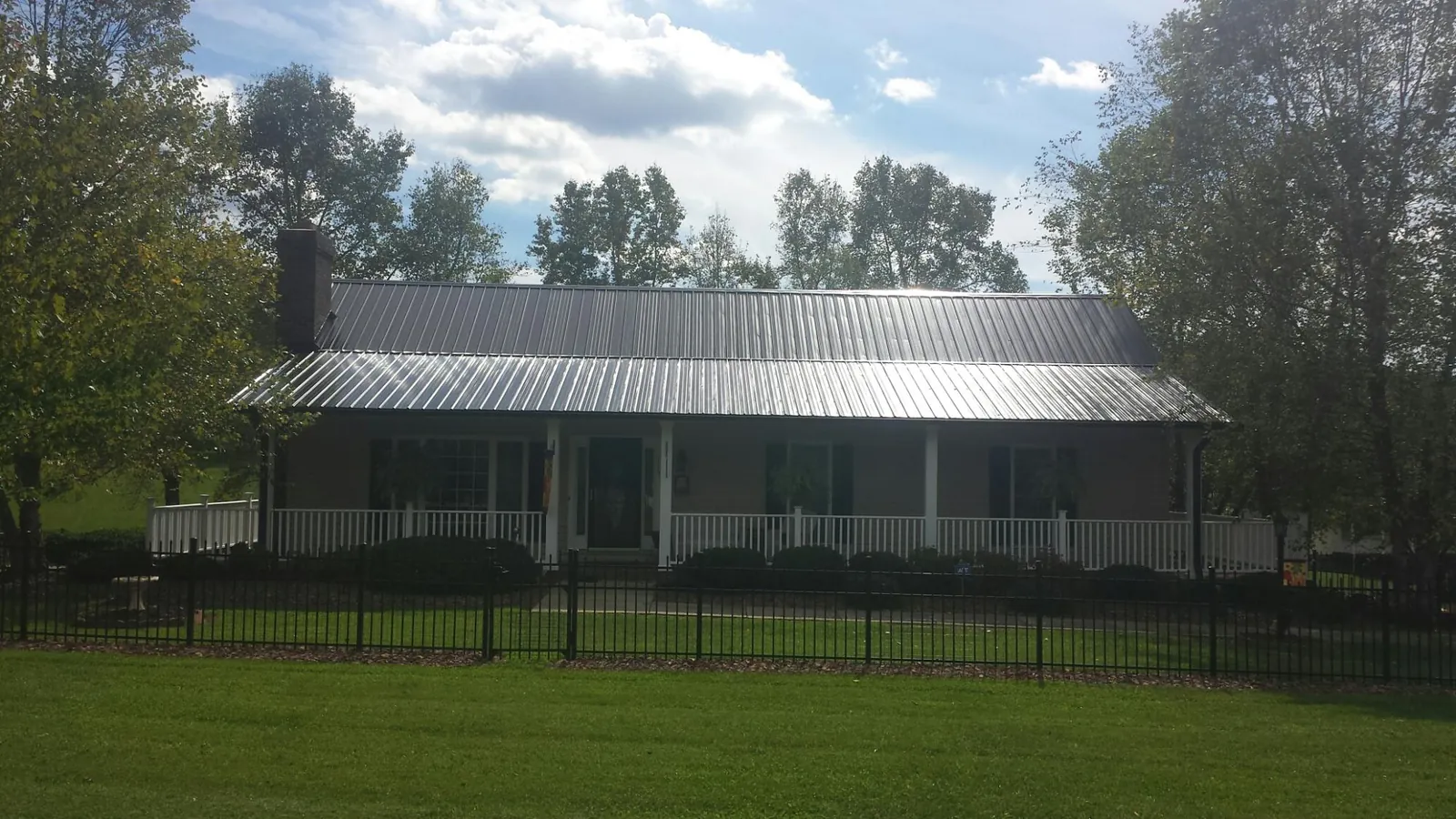 Gray metal roof on a brick ranch with a full width front porch — Gutter Guard Installation work by our crew in White Castle