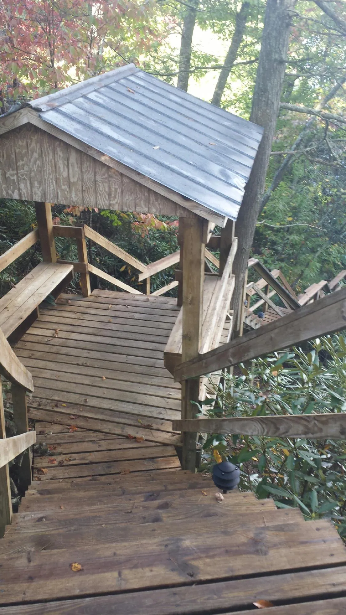 Metal roofed shelter over wooden steps on a wooded walkway — Skylight Repair & Installation work by our crew in White Castle