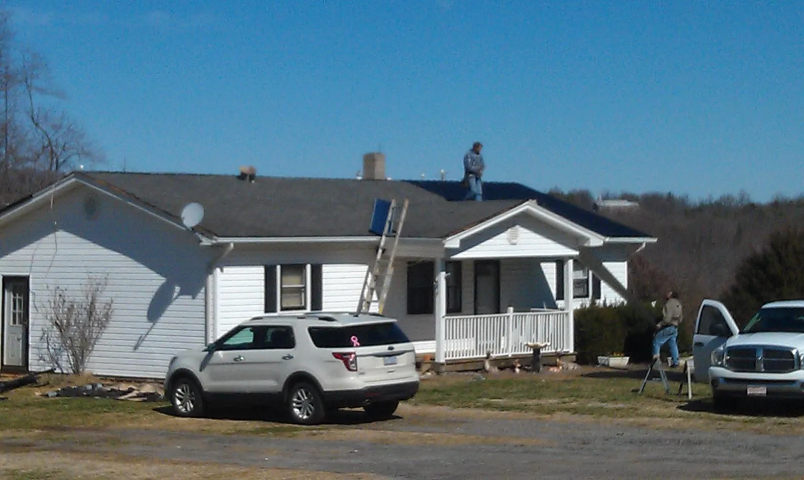 Roofers stripping shingles from a white ranch house roof in White Castle