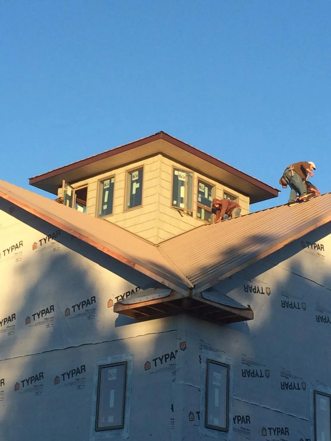 Roofers working around a rooftop cupola on a new metal roof at sunset — Roof Waterproofing in White Castle by Roofing Brothers